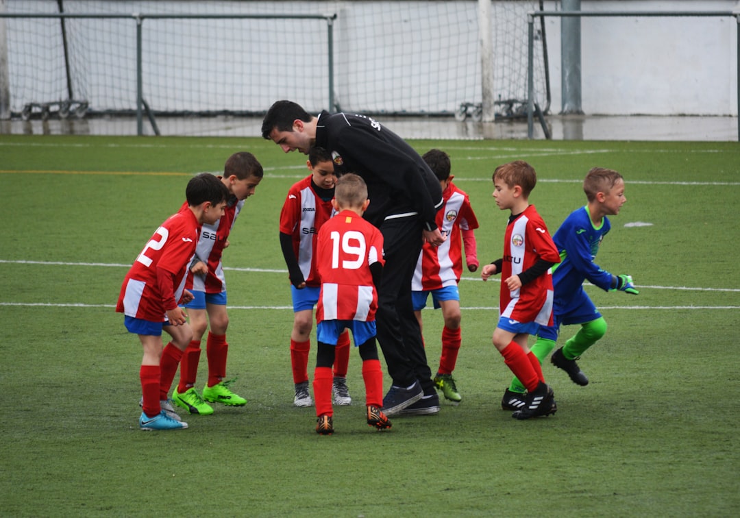 A parent cheering on their young child playing soccer on a sunny field, showcasing encouragement and support.