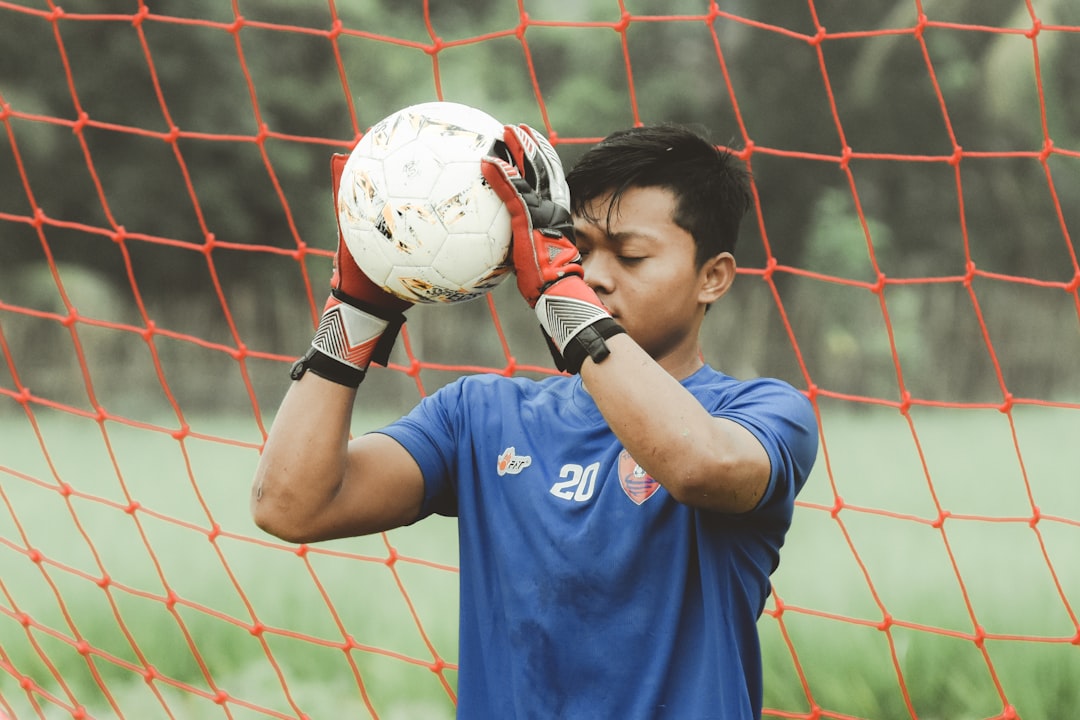 A young goalkeeper practicing catching a soccer ball during training, focused and determined on the field.