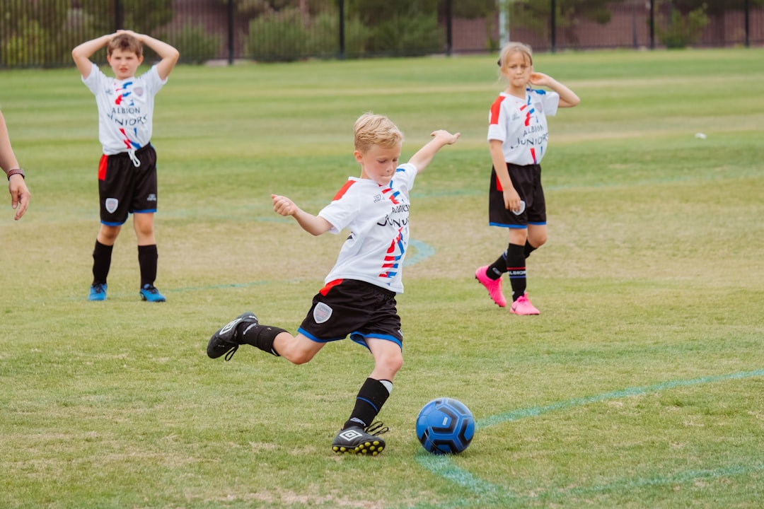 A young soccer player practicing on a field, demonstrating focus and determination while kicking a soccer ball.