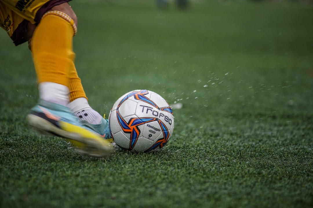 A young soccer player drinking water from a sports bottle on the field during practice.
